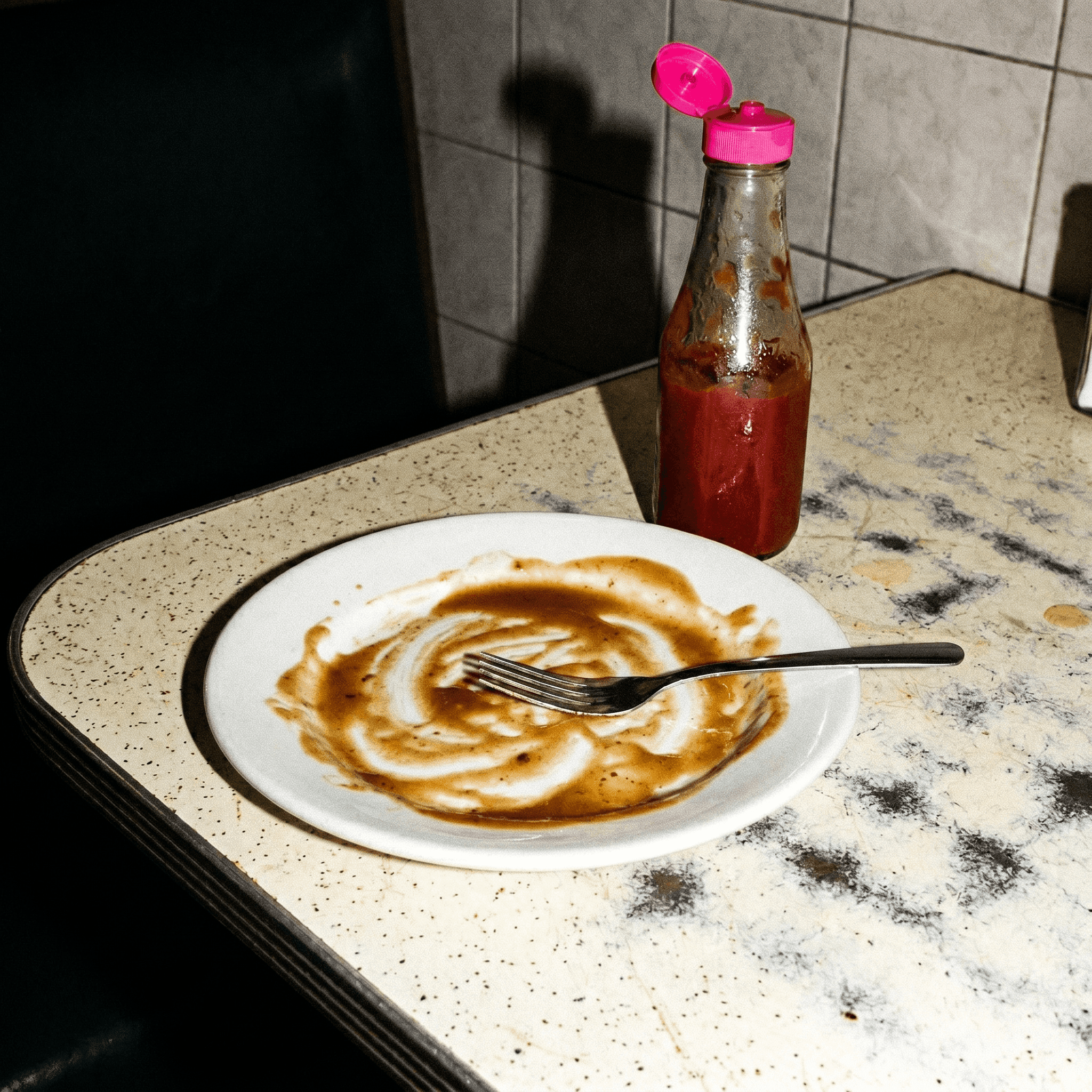 A diner plate scraped almost clean with a fork resting in it, shot with direct 2007 flash.