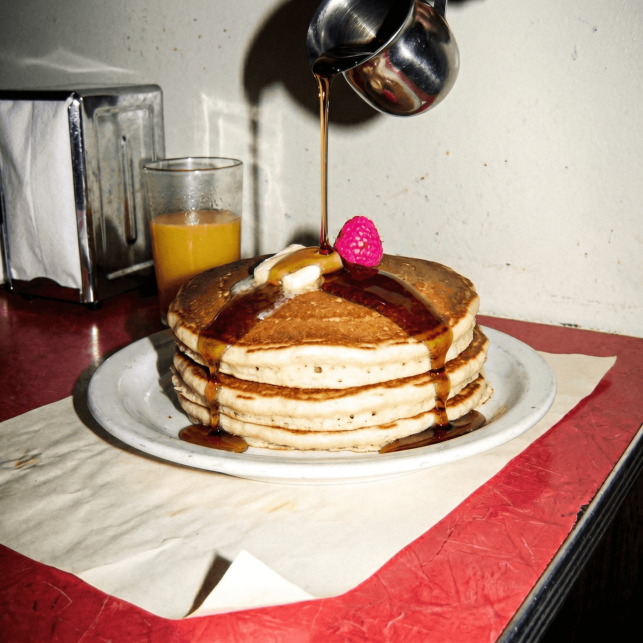 A towering short-stack of pancakes on a diner plate, shot with hard 2007 camera flash.